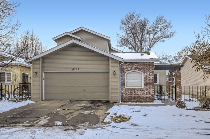 Single-story house with a brick accent, garage, and snow-covered yard.