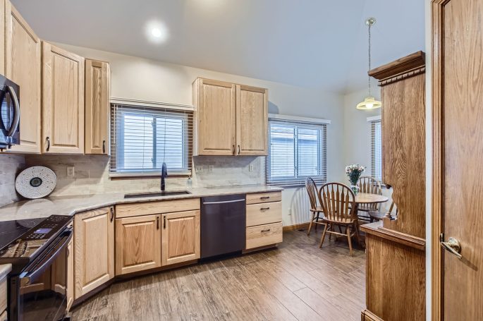 Bright kitchen with wooden cabinets, modern appliances, and a dining area by the window.