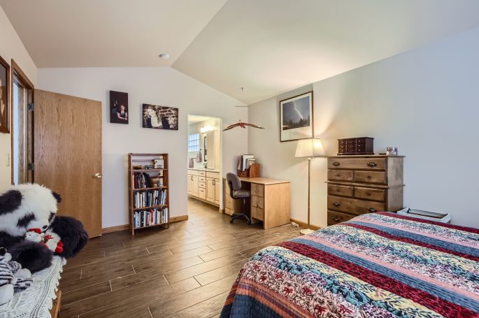 Cozy bedroom with wooden furniture, colorful quilt, and a panda plush toy.