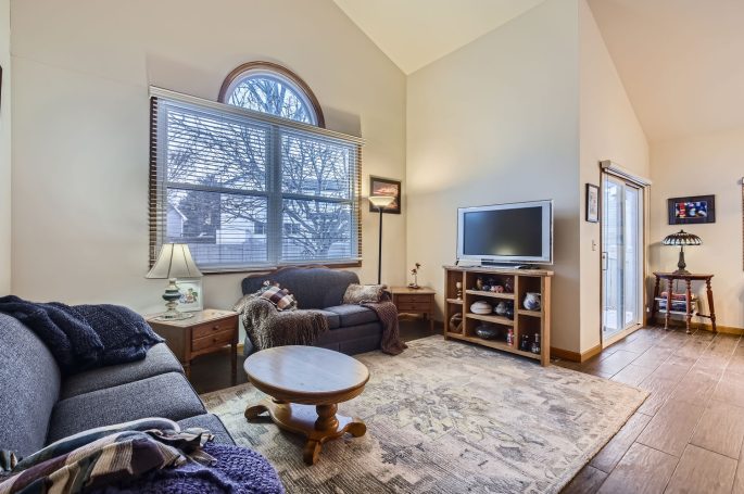 Cozy living room with a window, sofa, coffee table, and TV on a shelf.