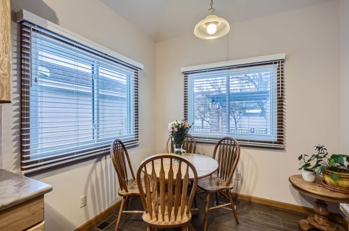 Cozy dining area with a round table, wooden chairs, and large windows.