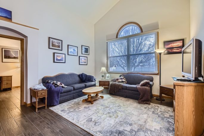 Cozy living room with two sofas, coffee table, and large window letting in natural light.